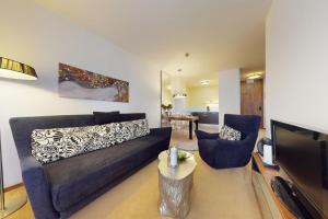 a living room with a blue couch and a tv at Apartmán Deluxe Jasná in Belá