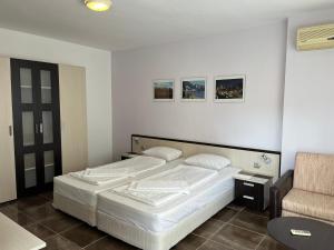 a bedroom with a white bed and a chair at kaLe in Ravda