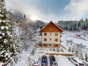 a house in the snow with cars parked next to it at Apartmán Deluxe Jasná in Belá