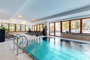 a pool in a hotel room with windows and a swimming pool at Apartmán Deluxe Jasná in Belá