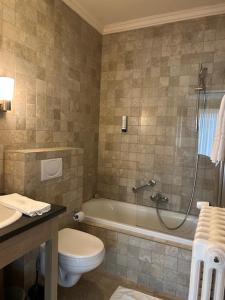 a bathroom with a tub and a toilet and a sink at Hotel Atlas in Zeebrugge +43 photos