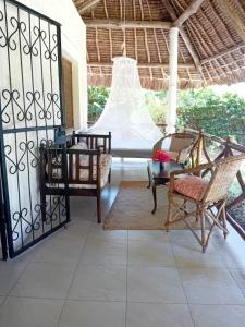 a porch with chairs and a table and a fence at Les Datchi Cottages in Diani Beach