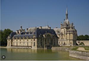 a large building with a tower on top of water at Le Antoine in Compiègne