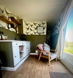 a kitchen with a chair and a clock on the wall at Cabin on the Moors in Llansannan