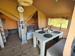 a room with a table and a bed in a tent at Luxe safaritent in Leersum
