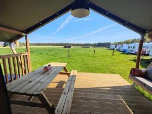 a picnic table on a deck with a view of a field at Luxe safaritent in Leersum