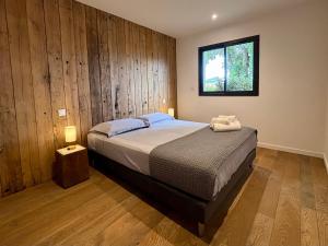 a bedroom with a bed with a wooden wall at Villa Sébastien by Intendance Excellency in Zonza +21 photos