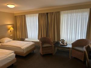 a hotel room with two beds and a table and chairs at Hotel Atlas in Zeebrugge