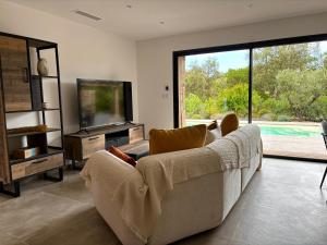 a living room with a couch and a television at Villa Sébastien by Intendance Excellency in Zonza