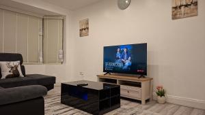 a living room with a flat screen tv on a wall at The White House in Moston