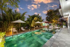 a pool at a hotel with chairs and umbrellas at Muoi Villa in Hiếu Nhơn