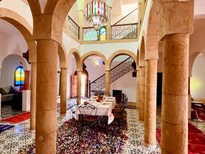 a dining room with a table and a chandelier at Palais Aya in Oulad Akkou