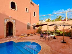 a house with a swimming pool and a table and umbrella at Palais Aya in Oulad Akkou