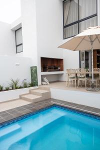 a swimming pool with a table and an umbrella at Oceana View at Oceans 3 Selfcatering Holiday Home in Rand Rifles