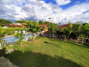 a yard with palm trees and a house with a pool at Casa Campestre Villa Alejandra in La Tebaida