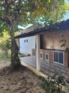 a brick building with a porch and a tree at Cantinho do tricolor in Saquarema