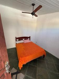 an orange bed in a room with a ceiling fan at Cantinho do tricolor in Saquarema