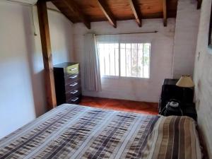 a bedroom with a bed with a dresser and a window at El Encuentro in Piriápolis