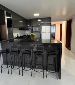 a kitchen with a black island with bar stools at Apartamento em Pomerode - 205 in Pomerode +5 photos
