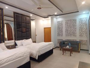 a hotel room with two beds and a chair at Grandy Boutique hotel in Islamabad