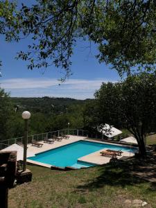 a swimming pool with tables and chairs and a tree at Balcón del Cerro Cabañas in La Falda