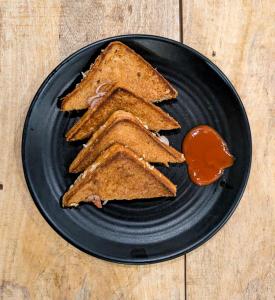a black plate with slices of bread and ketchup at Mosaic Hostel Varanasi in Varanasi