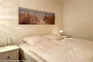 a white bed in a bedroom with two paintings on the wall at Luv und Lee in Schilksee