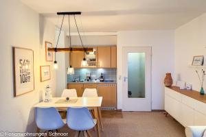 a kitchen with a white table and blue chairs at Luv und Lee in Schilksee