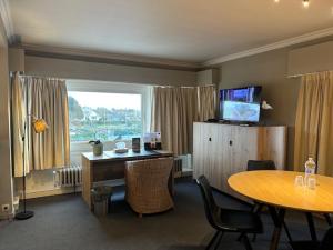 a room with a desk and a table and a window at Hotel Atlas in Zeebrugge