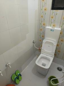 a small bathroom with a toilet and some green slippers at Swami Inn Lodging in Trimbak