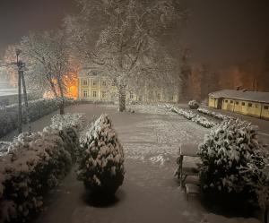 a snow covered park with benches and a building at Agroturystyka Maya in Gorzyca