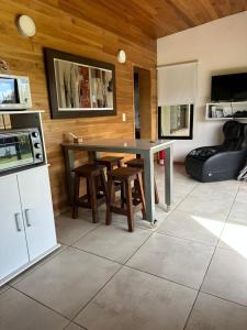 a kitchen with a table and stools in a room at Finca los Cauquenes Chascomus in Chascomús