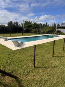a swimming pool with a bench in the grass at Finca los Cauquenes Chascomus in Chascomús