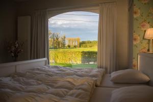a bedroom with a bed and a window with a view at 'Op de Borgt' met Finse Grill Kota in Wellen