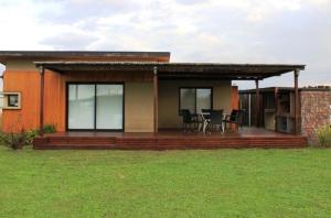a house with a deck with a table and chairs at Finca los Cauquenes Chascomus in Chascomús