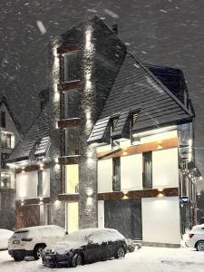 a house in the snow with cars parked in front at Central green in Divčibare