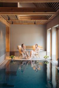 two people sitting on chairs next to a swimming pool at Broløkke Herregård in Humble