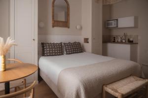 a bedroom with a white bed and a table and a table at Sézam Appart’Hôtel Saint-Malo in Saint Malo