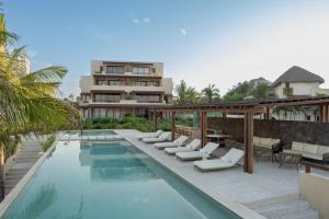 a swimming pool with lounge chairs next to a building at Luxury Apartment in Playa Blanca Zihuatanejo CAUMA in Zihuatanejo