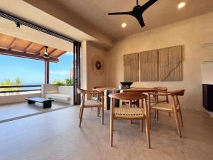 a dining room with tables and chairs and a large window at Luxury Apartment in Playa Blanca Zihuatanejo CAUMA in Zihuatanejo