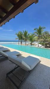 a row of lounge chairs next to a swimming pool at Luxury Apartment in Playa Blanca Zihuatanejo CAUMA in Zihuatanejo +11 photos