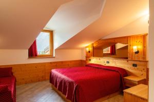a bedroom with a red bed and two windows at Hotel Ristorante Alla Nave in Lavis