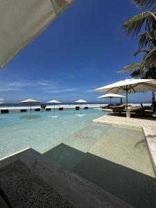 a swimming pool with umbrellas and the ocean at Luxury Apartment in Playa Blanca Zihuatanejo CAUMA in Zihuatanejo