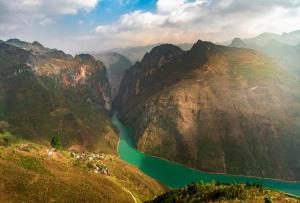 an aerial view of a mountain valley with a green river at Easy Ha Giang in Làng Lap
