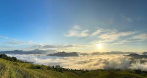 a view of a foggy valley with the sun above the clouds at Easy Ha Giang in Làng Lap