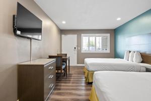 a hotel room with two beds and a flat screen tv at Hotel Milagro in Chula Vista
