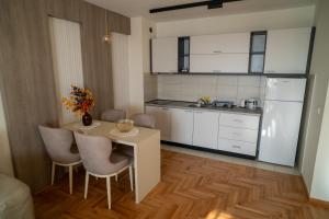a kitchen with a table and chairs and a refrigerator at Nedodjija apartman in Leskovac +4 photos