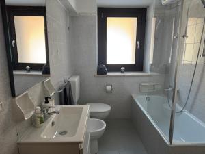 a bathroom with a sink and a toilet and a bath tub at Lago Maina Appartamenti in Sauris