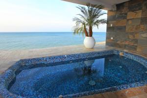 a pool with a palm tree in a vase next to the ocean at Edificio Poseidon Depto. Vista Lateral al Mar in Manta