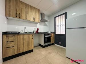 a kitchen with wooden cabinets and a white refrigerator at El Piso Bajo in San Juan de Moró